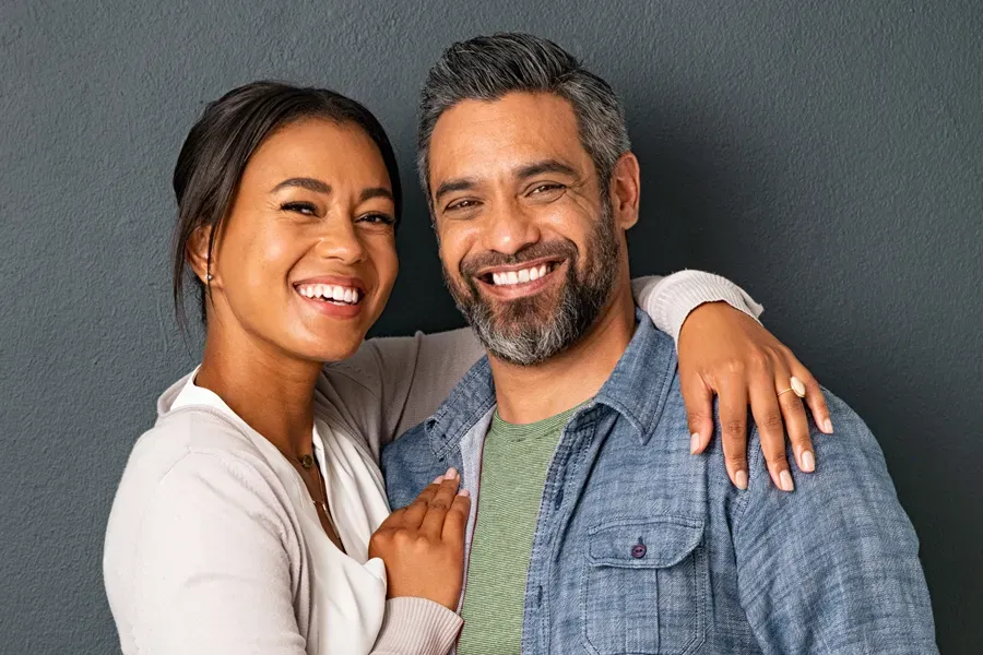 Bioidentical-Hormone-Therapy-Doctor A middle-aged couple with their arms around each other standing against a gray background and smiling, happy with the bioidentical hormone therapy they received from Stephen Beyer, DC in Mokena.