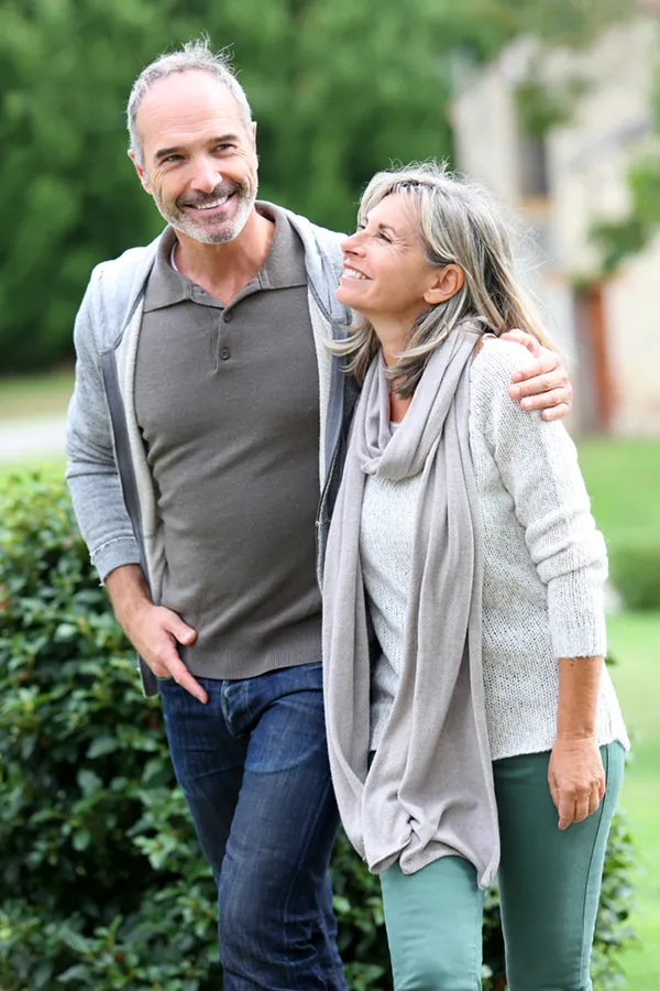 Bioidentical-Hormone-Therapy-Treatment A mature couple in gray toned clothes and jeans walk happily outside, happy with their successful bioidentical hormone treatments from Stephen Beyer, DC in Mokena.