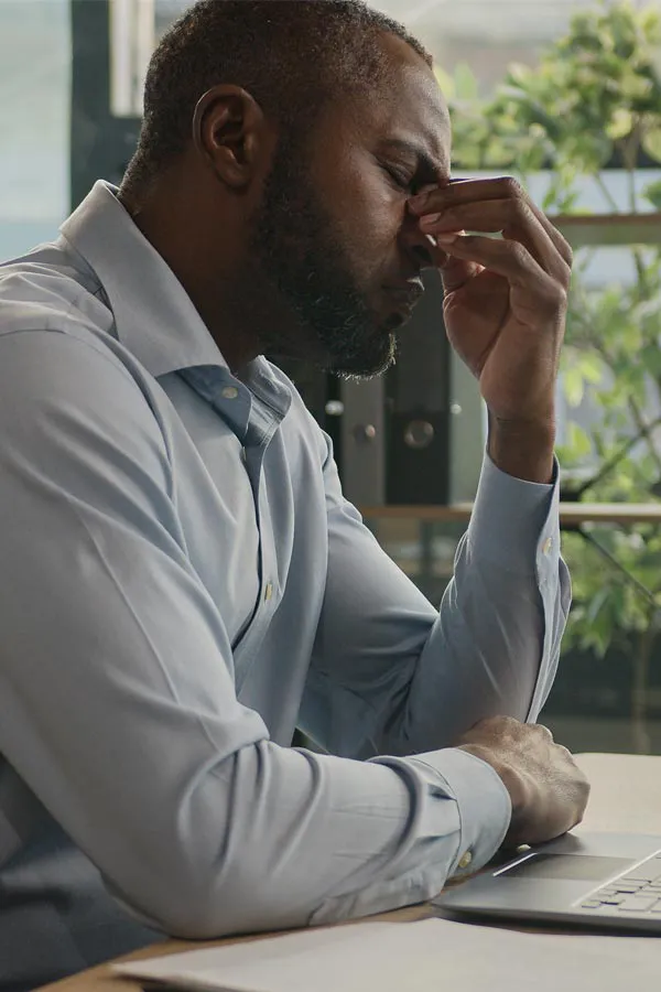 Chronic-Disease-Treatment A middle-aged black man sits at his desk holding his forehead in exhaustion. Get treatment for chronic disease from Stephen Beyer, DC in Mokena.