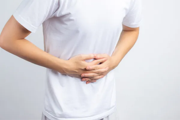 Irritable-Bowel-Syndrome-Clinic A person holding their stomach in visible discomfort against a plain background. Stephen Beyer, DC treats irritable bowel syndrome with functional medicine in Mokena.