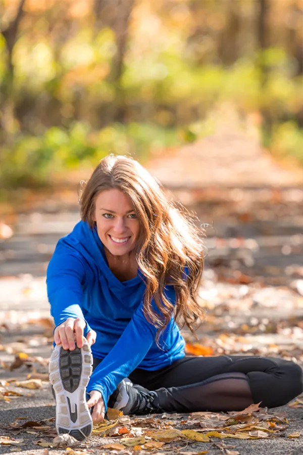 PRP-for-Sports-and-Orthopedics-Treatment A woman in blue warm ups stretching and preparing for a run on an outdoor trail. Get Platelet Rich Plasma (PRP) treatment for sports and orthopedics from Stephen Beyer, DC in Mokena.