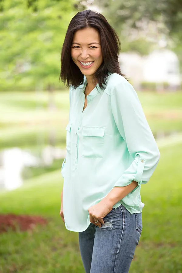 Perimenopause-Treatment A middle-aged brunette woman in a light green button-up shirt stands outside smiling, happy with her perimenopause treatment from Stephen Beyer, DC in Mokena.