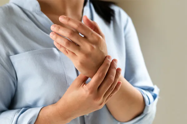 Rheumatoid-Arthritis-Clinic Close up of a woman in a blue blouse rubbing her wrist. Get rheumatoid arthritis treatment from Stephen Beyer, DC in Mokena.
