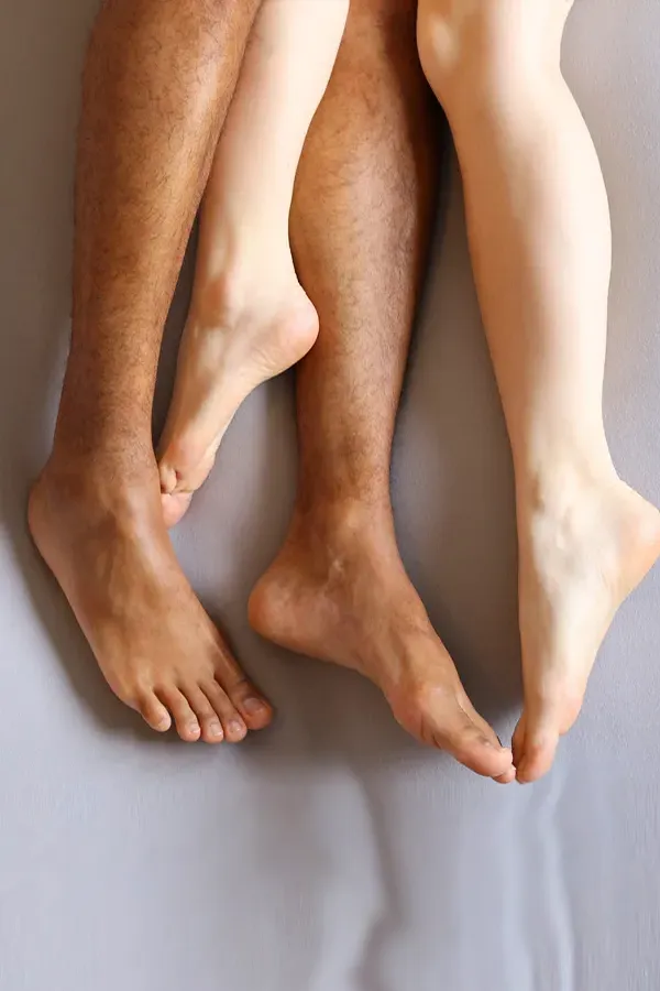 Shockwave-Treatment Photo from the knees to the feet of a couples nude legs entwined on a bed, representing shockwave treatment for erectile dysfunction from Stephen Beyer, DC in Mokena.