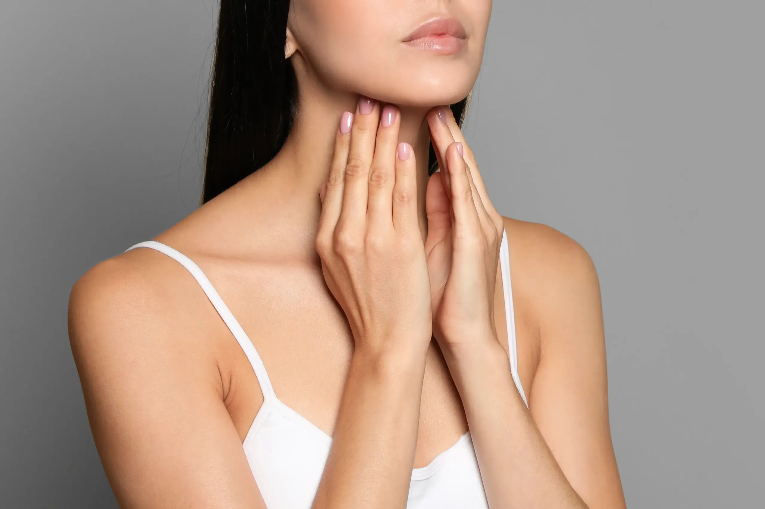 Thyroid-Doctor A woman in a white tank top touches her neck looking for signs of thyroid disorder. Get help for thyroid disorders from Stephen Beyer, DC in Mokena.